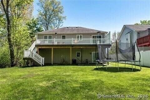 470 Nott St, Wethersfield, CT 06109 - rear view of house with a trampoline, a deck, a lawn, and stairs