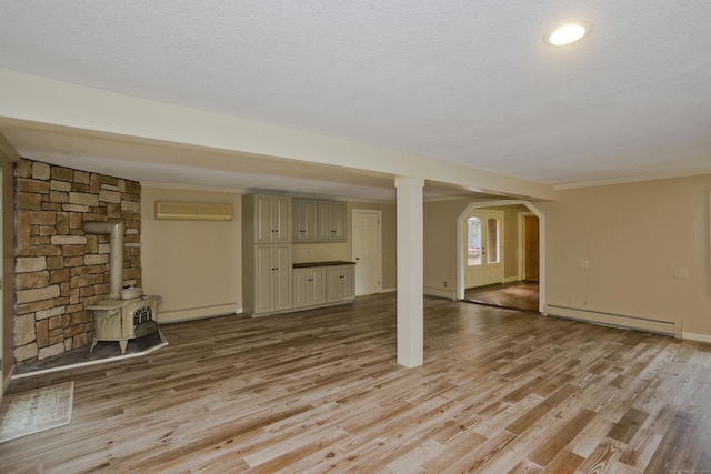 317 Turnpike Rd, Somers, CT 06071 - unfurnished living room with a baseboard heating unit, a wood stove, light wood-style floors, arched walkways, and a wall mounted AC