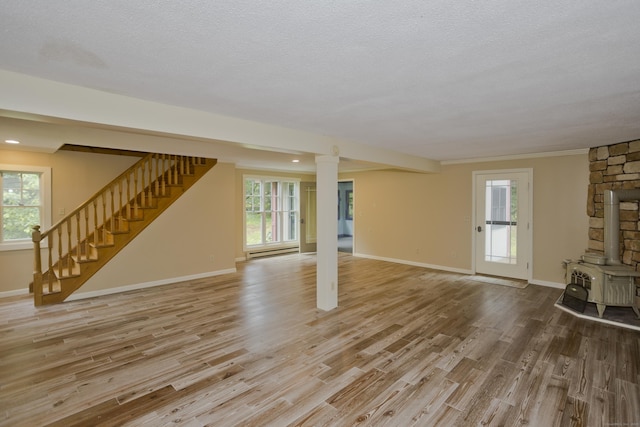 317 Turnpike Rd, Somers, CT 06071 - unfurnished living room featuring a wood stove, baseboard heating, wood finished floors, stairway, and a textured ceiling
