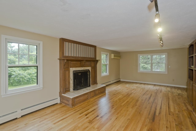 317 Turnpike Rd, Somers, CT 06071 - unfurnished living room featuring a baseboard heating unit, an AC wall unit, light wood finished floors, and plenty of natural light