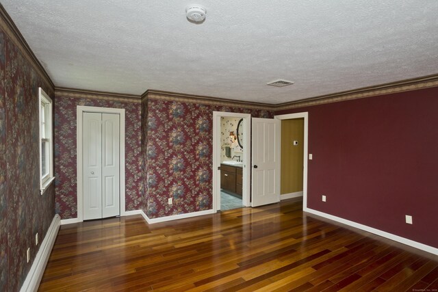 317 Turnpike Rd, Somers, CT 06071 - unfurnished bedroom with hardwood / wood-style floors, a textured ceiling, a baseboard radiator, wallpapered walls, and ornamental molding