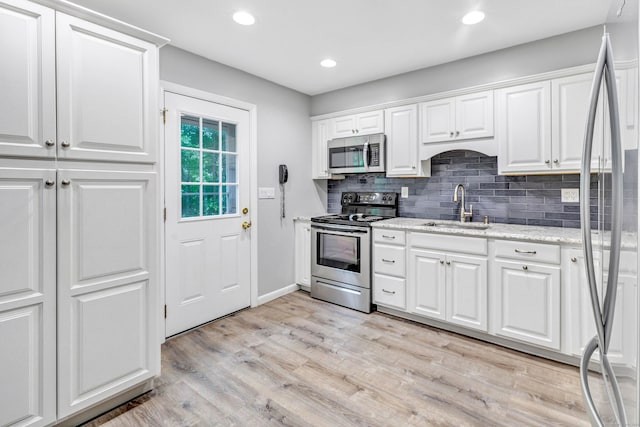 343 Steiner St, Fairfield, CT 06825 - kitchen with appliances with stainless steel finishes, decorative backsplash, white cabinetry, light wood-style floors, and light stone counters