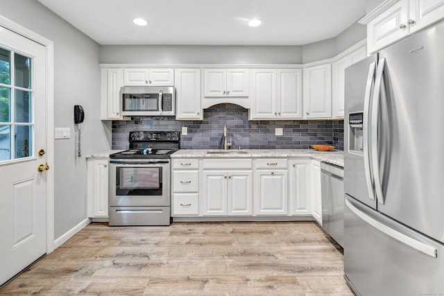 343 Steiner St, Fairfield, CT 06825 - kitchen featuring appliances with stainless steel finishes, white cabinets, decorative backsplash, light wood finished floors, and recessed lighting