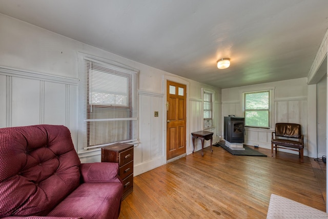 63 Fox Trl, Coventry, CT 06238 - living area with a decorative wall, a wood stove, light wood-style floors, and wainscoting