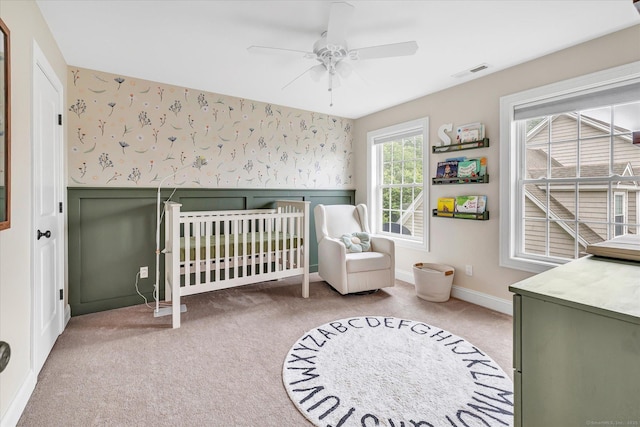 27 Bartlett Ln Unit 27, Shelton, CT 06484 - bedroom with wallpapered walls, light colored carpet, ceiling fan, a crib, and a wainscoted wall
