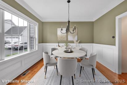 27 Bartlett Ln Unit 27, Shelton, CT 06484 - dining area featuring healthy amount of natural light, a chandelier, wainscoting, wood finished floors, and crown molding