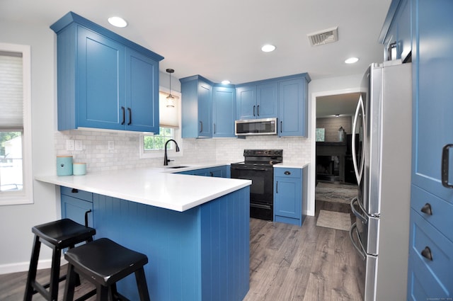 503 Mulberry St, Southington, CT 06479 - kitchen with appliances with stainless steel finishes, blue cabinetry, a peninsula, tasteful backsplash, and wood finished floors
