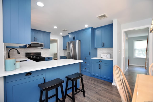 503 Mulberry St, Southington, CT 06479 - kitchen featuring appliances with stainless steel finishes, a peninsula, blue cabinets, decorative backsplash, and light countertops