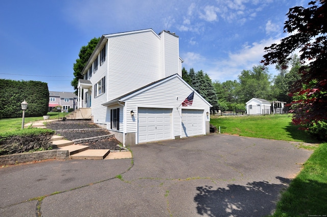 503 Mulberry St, Southington, CT 06479 - view of home's exterior featuring a chimney, asphalt driveway, a yard, and a garage