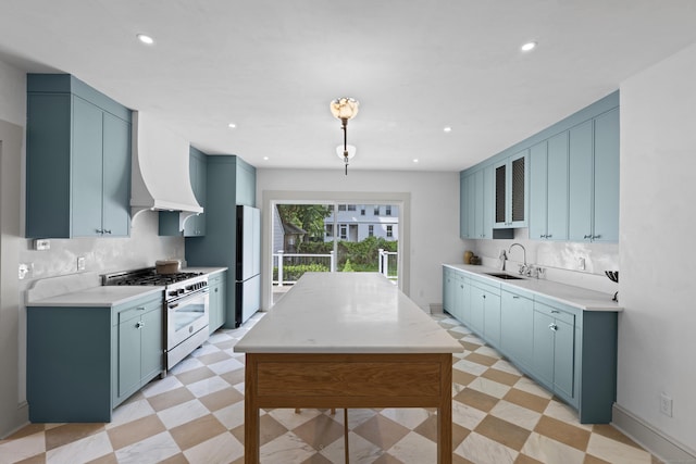 119 Westwood Rd, New Haven, CT 06515 - kitchen with stainless steel gas range oven, light floors, blue cabinets, premium range hood, and freestanding refrigerator