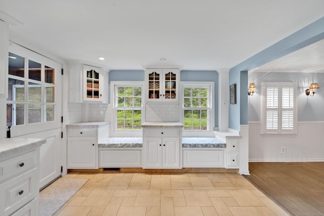 268 Hattertown Rd, Monroe, CT 06468 - interior space with wainscoting, glass insert cabinets, white cabinetry, backsplash, and light stone countertops