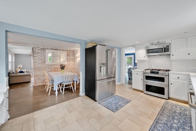 268 Hattertown Rd, Monroe, CT 06468 - kitchen featuring appliances with stainless steel finishes, white cabinetry, backsplash, and light countertops