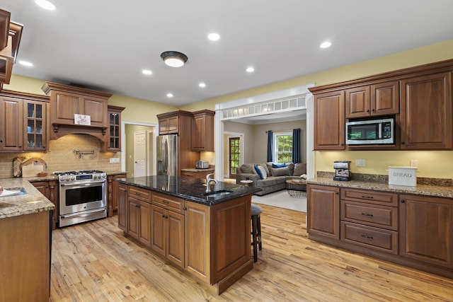 28 Hoop Pole Hill Rd, Chester, CT 06412 - kitchen with appliances with stainless steel finishes, light wood-style flooring, a center island with sink, glass insert cabinets, and a breakfast bar area