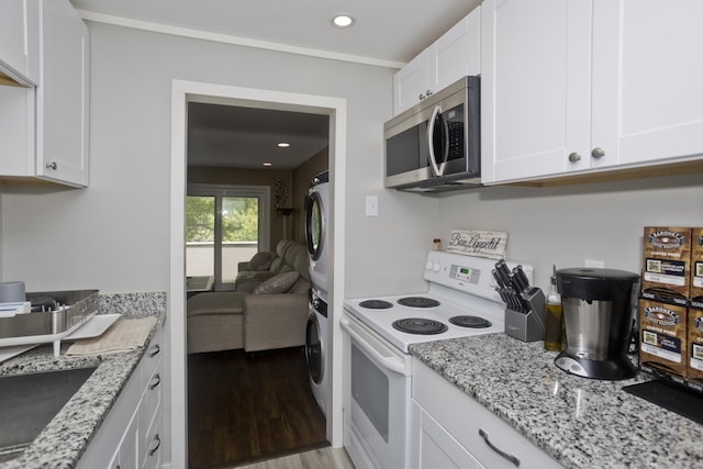 73 Landing Cir Unit 73, Suffield, CT 06078 - kitchen featuring stainless steel microwave, white electric range, stacked washing machine and dryer, white cabinets, and light wood-style floors