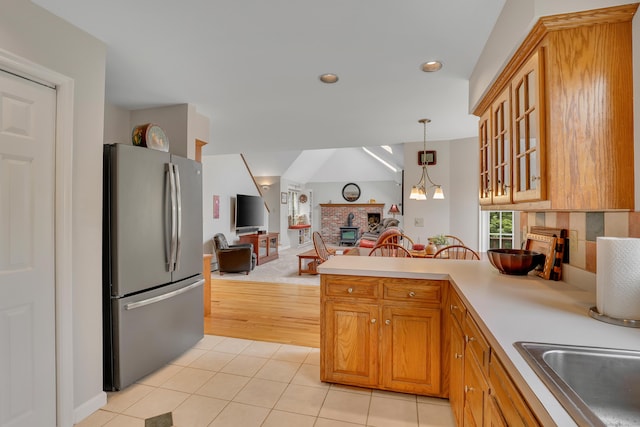 344 Oxbow Rd, Haddam, CT 06422 - kitchen with freestanding refrigerator, a brick fireplace, light tile patterned flooring, glass insert cabinets, and open floor plan