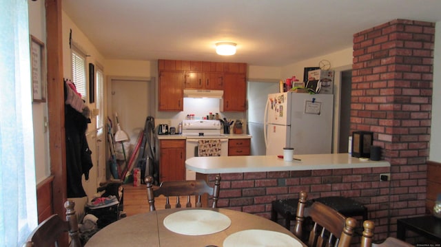 195 E Pearl St, Torrington, CT 06790 - kitchen with white appliances, under cabinet range hood, a peninsula, and brown cabinetry