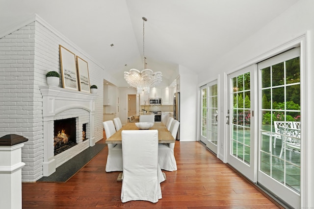 566 Hoyt St, Darien, CT 06820 - dining room with a fireplace, a chandelier, vaulted ceiling, and wood finished floors