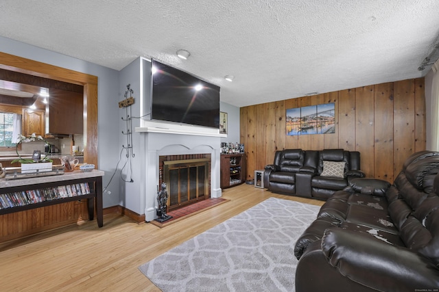 32 Butternut Ridge Rd, Waterbury, CT 06706 - living room with wood finished floors, wood walls, a glass covered fireplace, and a textured ceiling