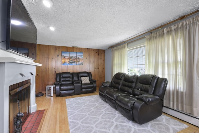 32 Butternut Ridge Rd, Waterbury, CT 06706 - living area with baseboard heating, a textured ceiling, wooden walls, wood finished floors, and a fireplace