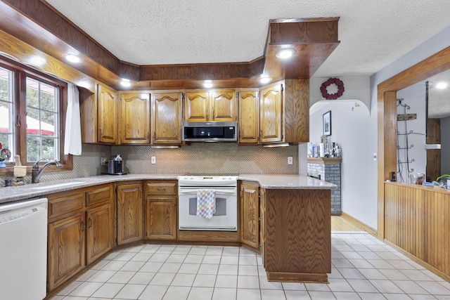 32 Butternut Ridge Rd, Waterbury, CT 06706 - kitchen featuring white appliances, a textured ceiling, brown cabinets, backsplash, and light countertops