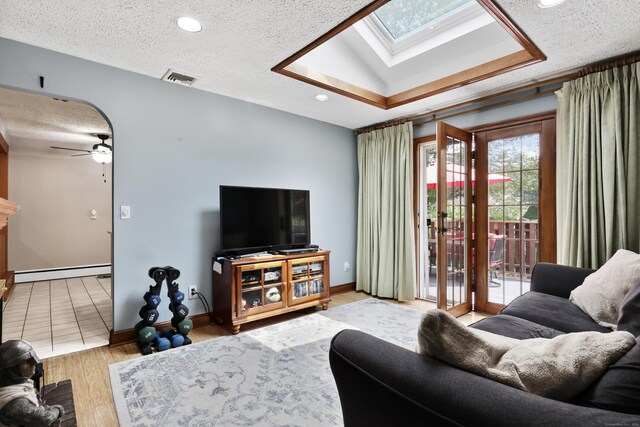 32 Butternut Ridge Rd, Waterbury, CT 06706 - living area with a skylight, a baseboard heating unit, ceiling fan, a textured ceiling, and wood finished floors