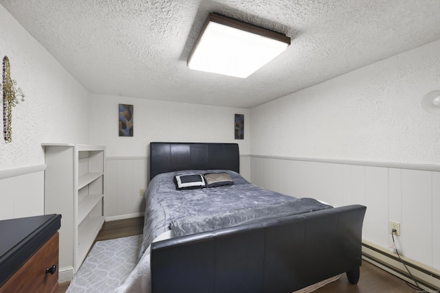 32 Butternut Ridge Rd, Waterbury, CT 06706 - bedroom with baseboard heating, a textured ceiling, a textured wall, a wainscoted wall, and dark wood finished floors