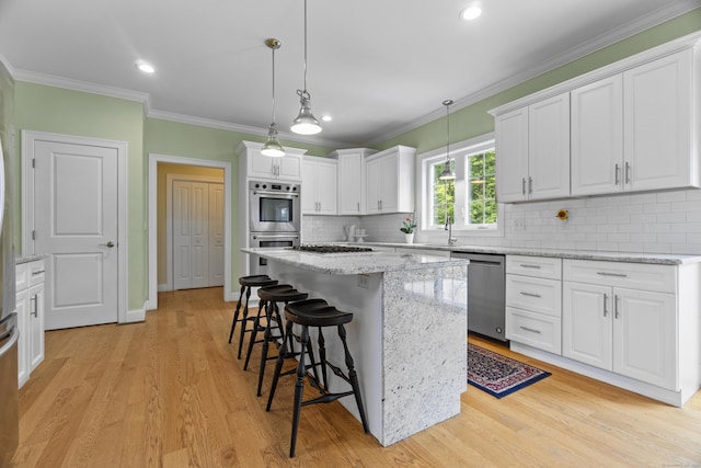 257 Ichabod Rd, Southbury, CT 06488 - kitchen with stainless steel appliances, white cabinets, a kitchen bar, light wood-style floors, and ornamental molding