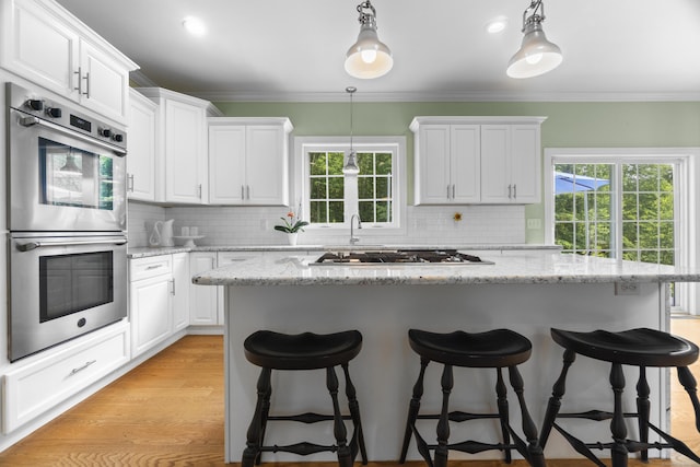 257 Ichabod Rd, Southbury, CT 06488 - kitchen with stainless steel appliances, crown molding, a breakfast bar, white cabinetry, and decorative backsplash