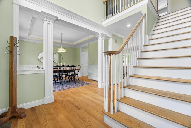 257 Ichabod Rd, Southbury, CT 06488 - stairs with wood finished floors, ornate columns, ornamental molding, a wainscoted wall, and a decorative wall