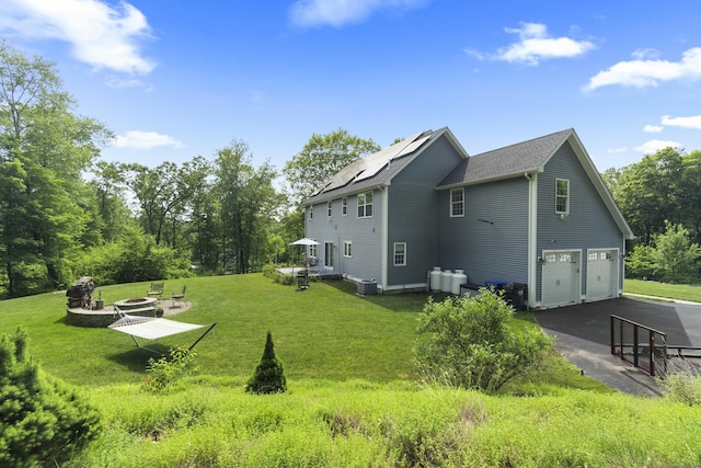 257 Ichabod Rd, Southbury, CT 06488 - view of property exterior featuring an outdoor fire pit, a garage, a yard, driveway, and solar panels
