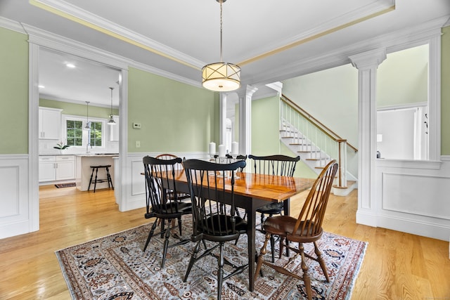 257 Ichabod Rd, Southbury, CT 06488 - dining room featuring ornate columns, ornamental molding, a decorative wall, light wood-style floors, and a wainscoted wall