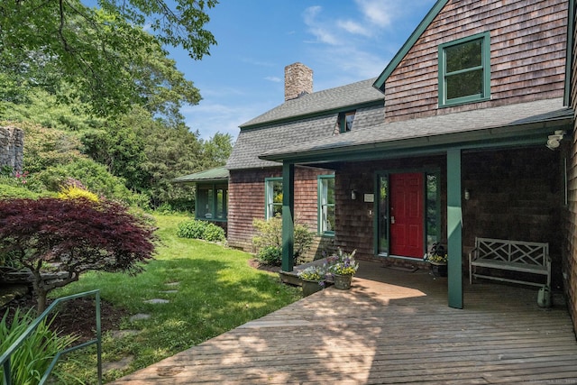 77 E Wharf Rd, Madison, CT 06443 - view of exterior entry with a chimney, roof with shingles, a lawn, and a deck