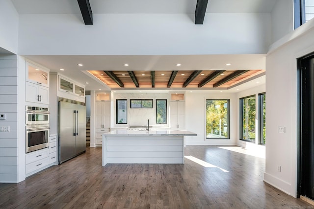 103 Chalybes Rd W, Roxbury, CT 06783 - kitchen featuring appliances with stainless steel finishes, beam ceiling, white cabinets, an island with sink, and glass insert cabinets