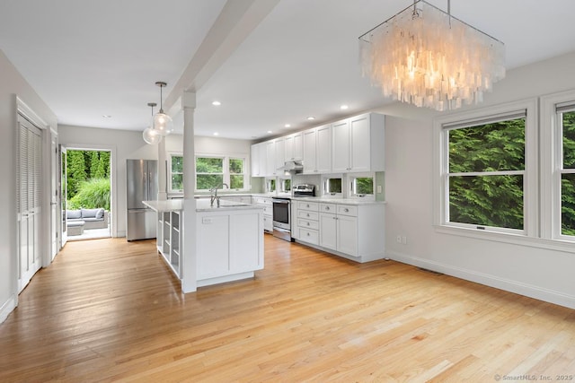 19 Sherwood Dr, Westport, CT 06880 - kitchen with appliances with stainless steel finishes, light countertops, light wood-style flooring, a chandelier, and under cabinet range hood