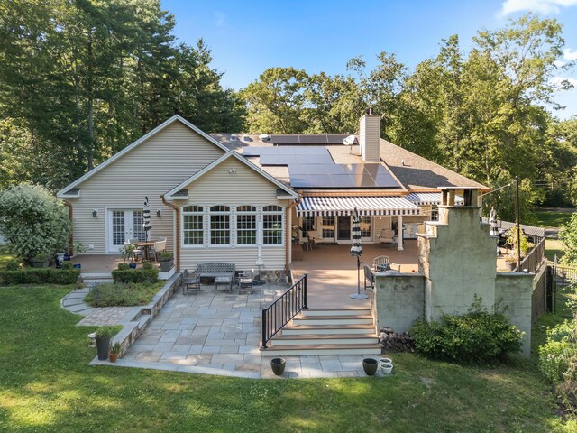 45 Shaker Ct, Guilford, CT 06437 - back of property with a patio, a lawn, roof mounted solar panels, a chimney, and a wooden deck