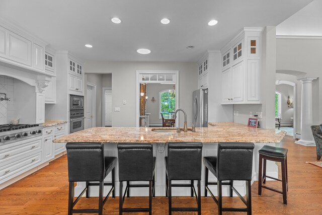 45 Shaker Ct, Guilford, CT 06437 - kitchen with appliances with stainless steel finishes, a kitchen bar, a peninsula, white cabinets, and glass insert cabinets