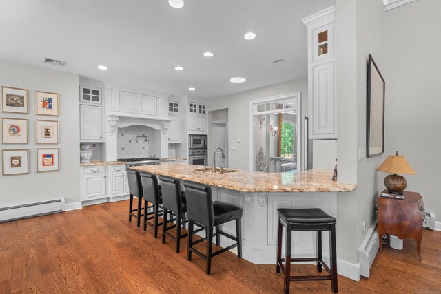 45 Shaker Ct, Guilford, CT 06437 - kitchen featuring appliances with stainless steel finishes, a peninsula, white cabinetry, glass insert cabinets, and a breakfast bar
