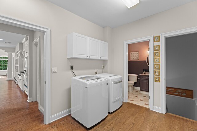 45 Shaker Ct, Guilford, CT 06437 - laundry area featuring cabinet space, washing machine and clothes dryer, light wood-style flooring, and decorative columns
