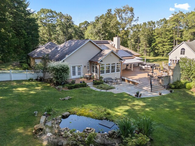 45 Shaker Ct, Guilford, CT 06437 - back of property featuring french doors, a deck, solar panels, a patio area, and a chimney