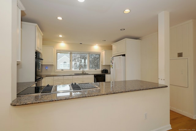 73 Harbour View Pl Unit 73, Stratford, CT 06615 - kitchen featuring black appliances, a peninsula, dark stone counters, recessed lighting, and light wood-style flooring