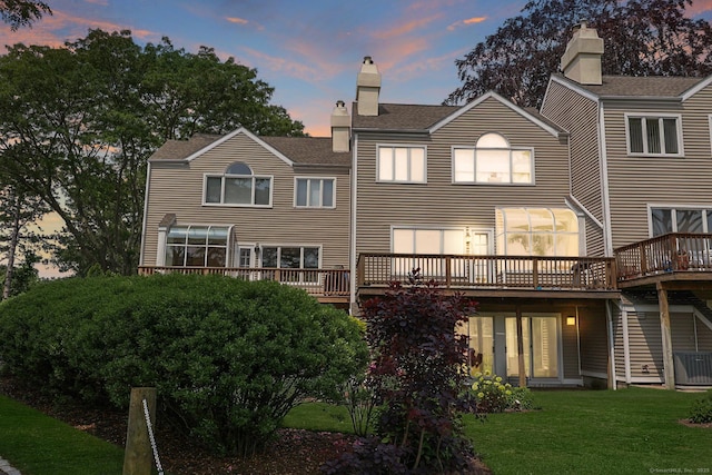 73 Harbour View Pl Unit 73, Stratford, CT 06615 - back of house at dusk featuring a yard, a deck, a chimney, and a shingled roof