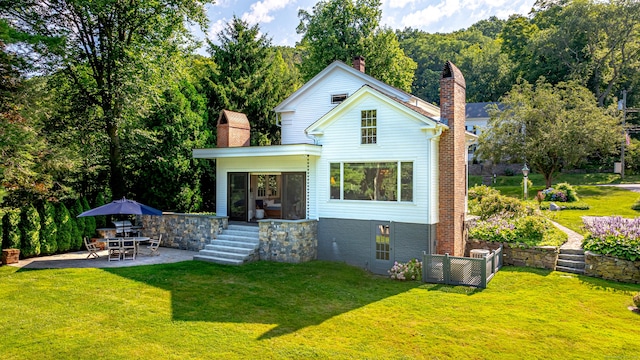 55 Main St, East Haddam, CT 06423 - rear view of property with a chimney, a patio, a lawn, and brick siding