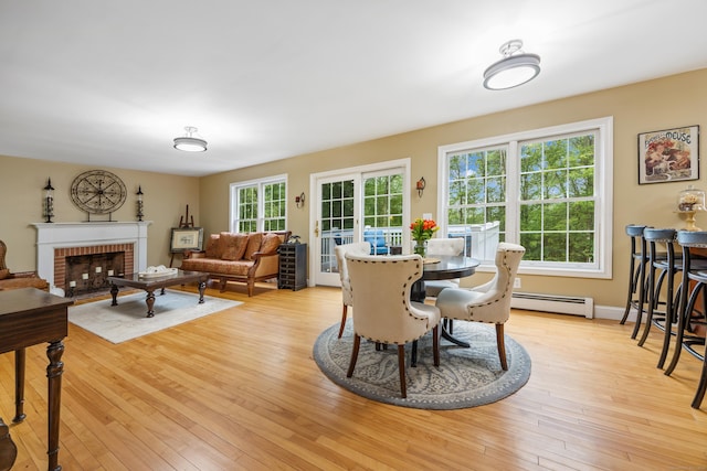 5 Goldfinch Ter, East Lyme, CT 06333 - dining area with baseboard heating, light wood-type flooring, and a brick fireplace
