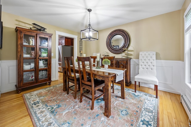 5 Goldfinch Ter, East Lyme, CT 06333 - dining space with baseboard heating, a wainscoted wall, light wood-style floors, and a decorative wall