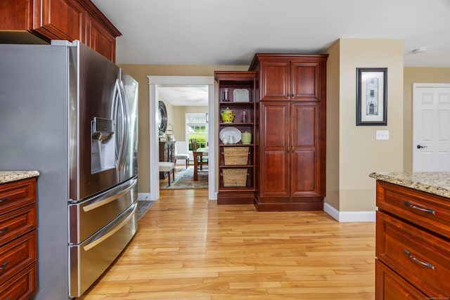 5 Goldfinch Ter, East Lyme, CT 06333 - kitchen with stainless steel refrigerator with ice dispenser, reddish brown cabinets, light wood-style floors, light stone countertops, and open shelves