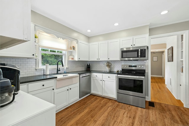 1027 Monroe Tpke, Monroe, CT 06468 - kitchen with appliances with stainless steel finishes, white cabinetry, light wood-type flooring, tasteful backsplash, and crown molding