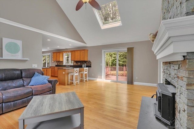97 Cherry Swamp Rd, East Haddam, CT 06469 - living room with ceiling fan, high vaulted ceiling, light wood-style flooring, a skylight, and a wood stove