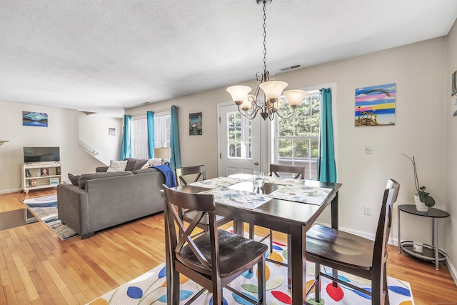 663 W Ave Unit A24, Milford, CT 06461 - dining room featuring a chandelier, light wood-style floors, and a textured ceiling