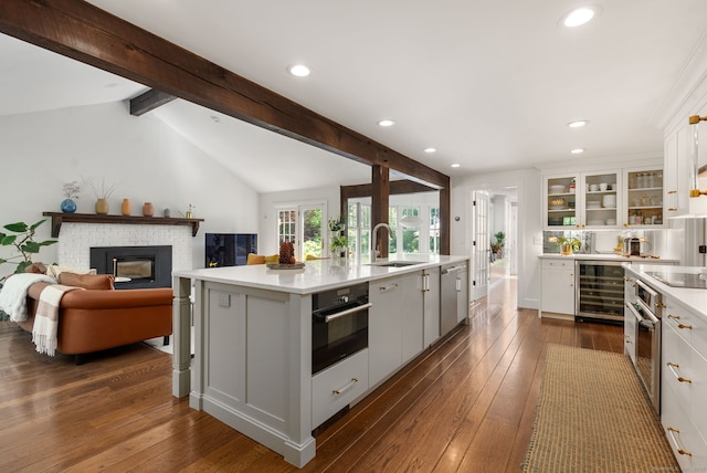 56 Turtleback Rd, Wilton, CT 06897 - kitchen featuring beverage cooler, black appliances, light countertops, white cabinets, and a brick fireplace
