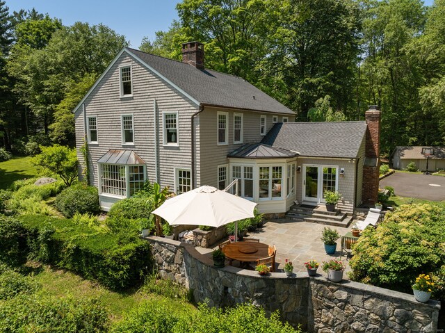 56 Turtleback Rd, Wilton, CT 06897 - rear view of house with a patio, a chimney, roof with shingles, entry steps, and a standing seam roof